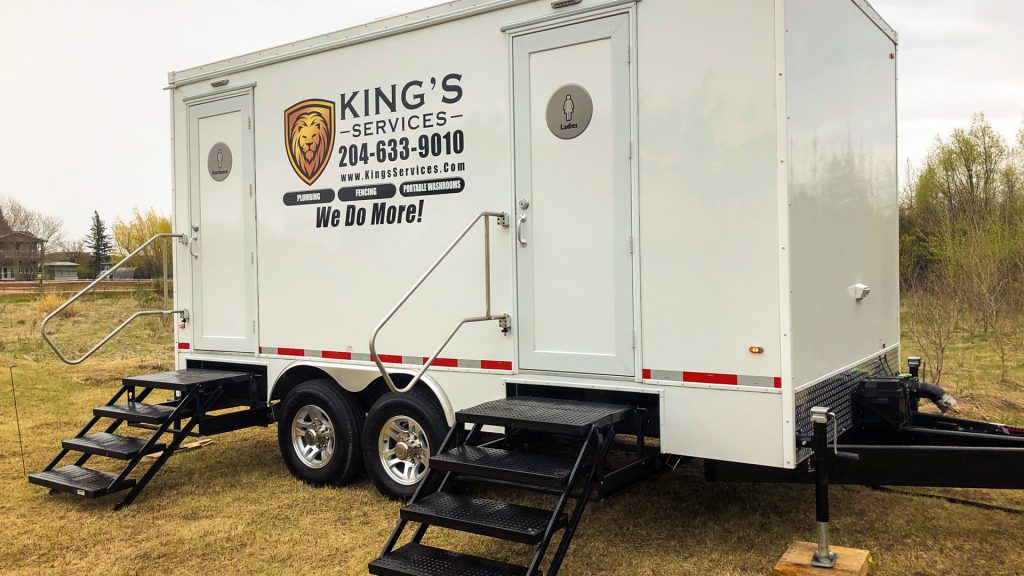 White King’s portable restroom trailer with black steps, parked on grass outdoors.